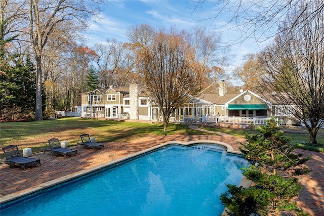 outdoor pool with a patio area and a yard