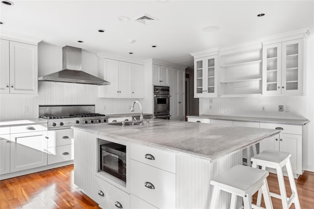 kitchen with black microwave, cooktop, stainless steel double oven, wall chimney exhaust hood, and a sink