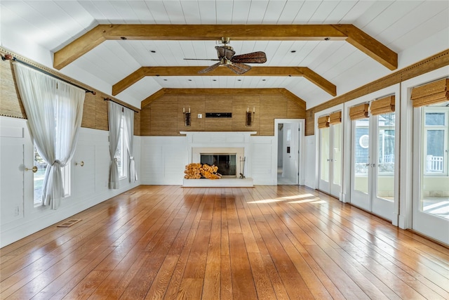 unfurnished living room featuring visible vents, a ceiling fan, hardwood / wood-style flooring, lofted ceiling with beams, and a glass covered fireplace