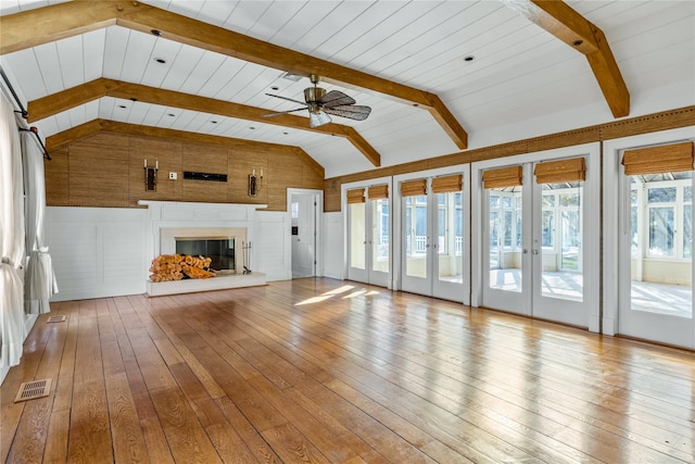 unfurnished living room with visible vents, vaulted ceiling with beams, ceiling fan, hardwood / wood-style flooring, and a glass covered fireplace