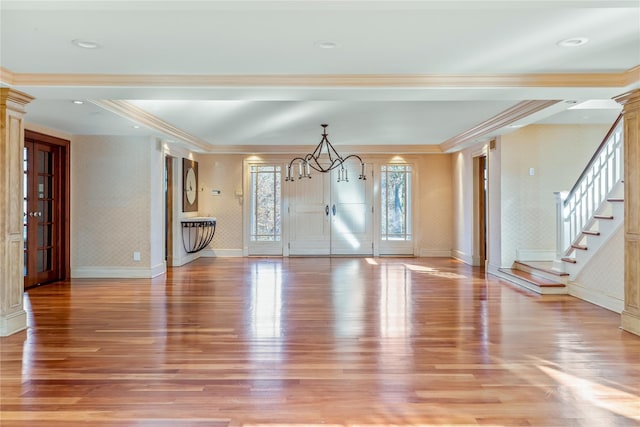 unfurnished living room featuring baseboards, light wood finished floors, stairs, and ornate columns