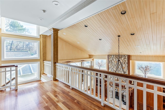 hallway featuring ornate columns, wooden ceiling, wood finished floors, and a wealth of natural light