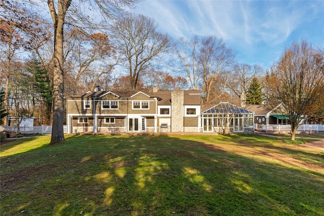 view of front facade with stone siding, a chimney, a front yard, and fence