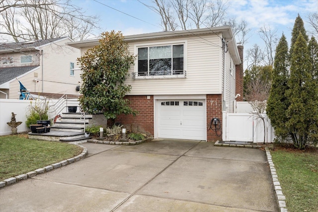 view of front of property with brick siding, driveway, a garage, and fence