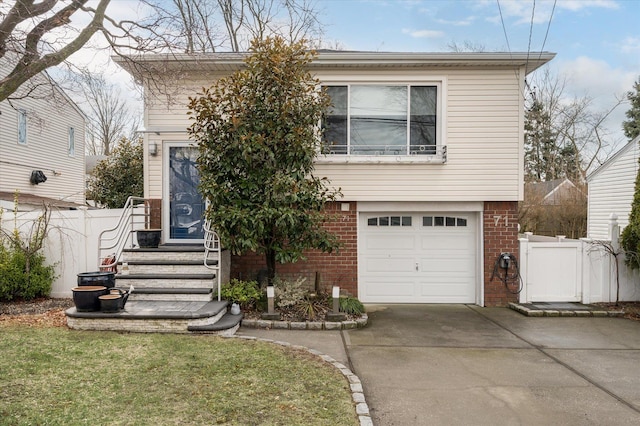 view of front of house with an attached garage, fence, brick siding, and driveway