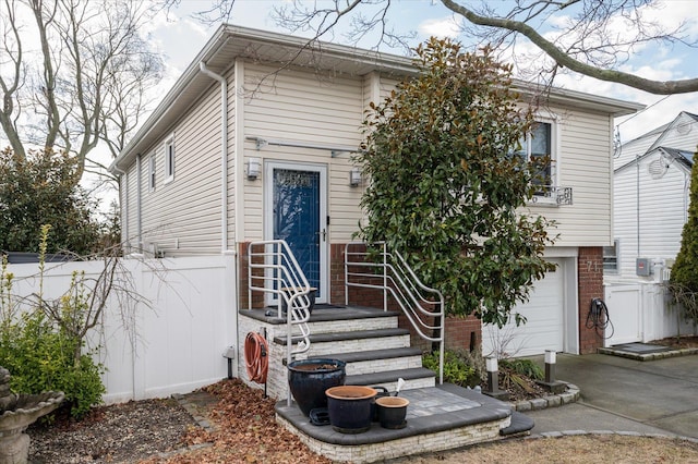 view of front of property featuring driveway, brick siding, an attached garage, and fence