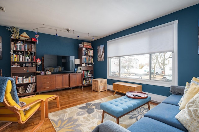 living room with visible vents, baseboards, wood finished floors, and track lighting