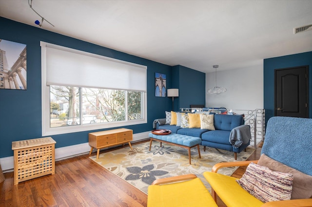 living room with visible vents, baseboards, and wood finished floors