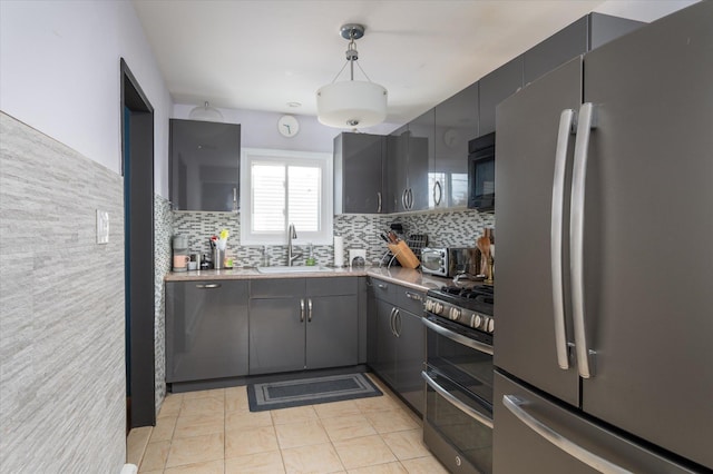 kitchen with gray cabinetry, a sink, backsplash, appliances with stainless steel finishes, and light countertops