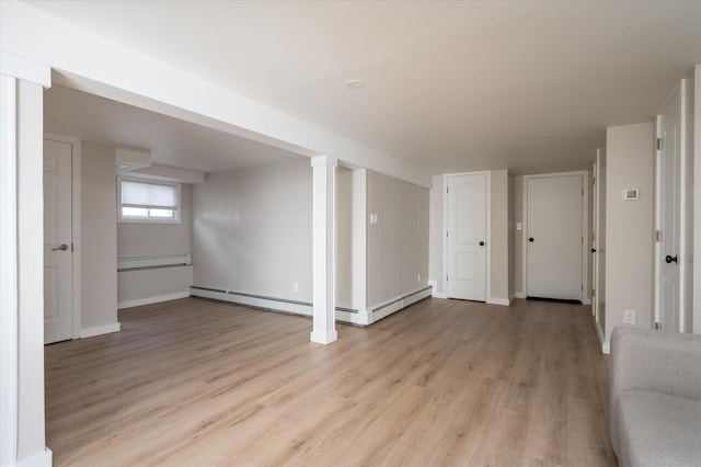 unfurnished living room featuring light wood finished floors, baseboards, and a baseboard radiator