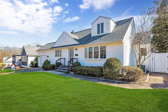 view of front of house featuring an attached garage, roof with shingles, a front lawn, and fence