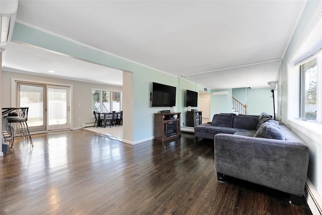 living area with a baseboard heating unit, a healthy amount of sunlight, dark wood finished floors, and stairs