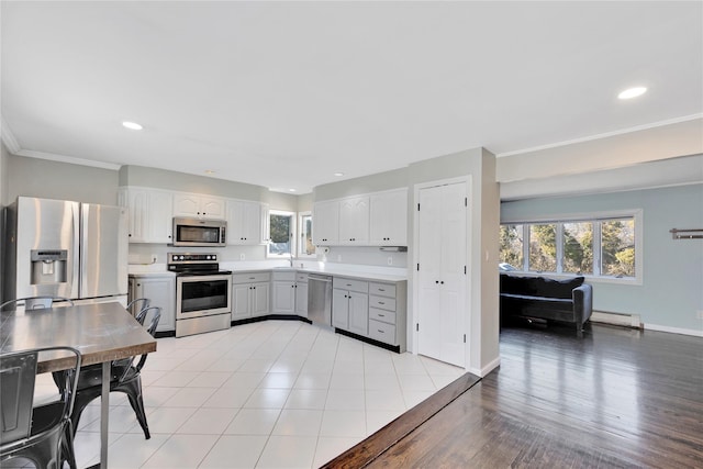 kitchen featuring a healthy amount of sunlight, stainless steel appliances, a baseboard heating unit, and light countertops