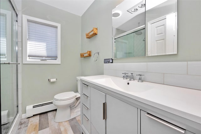 bathroom featuring a shower stall, vanity, a baseboard heating unit, and toilet