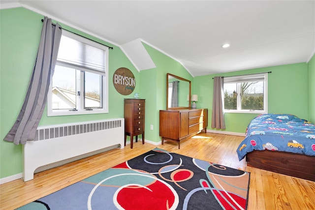 bedroom featuring radiator, baseboards, lofted ceiling, and wood-type flooring