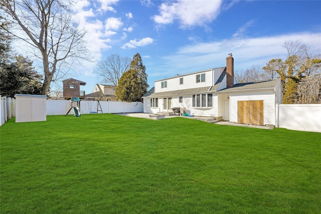 back of house featuring a patio, a lawn, a fenced backyard, and a playground