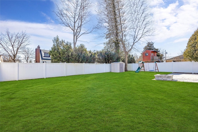 view of yard featuring an outbuilding, a fenced backyard, and a playground