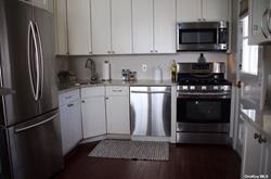 kitchen featuring dark wood finished floors, white cabinets, appliances with stainless steel finishes, and a sink