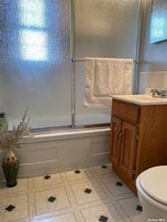 bathroom with tile patterned flooring, toilet, vanity, and bath / shower combo with glass door