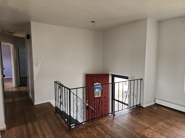 staircase with a baseboard heating unit, baseboards, and wood finished floors