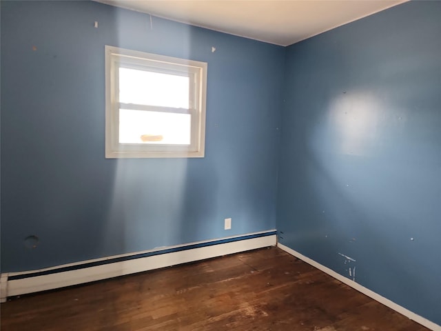 unfurnished room with a baseboard heating unit and wood finished floors