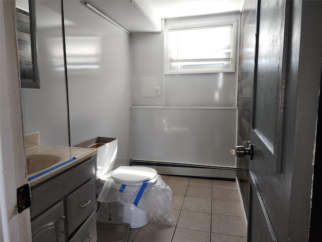 half bathroom with tile patterned floors, a baseboard heating unit, toilet, and vanity