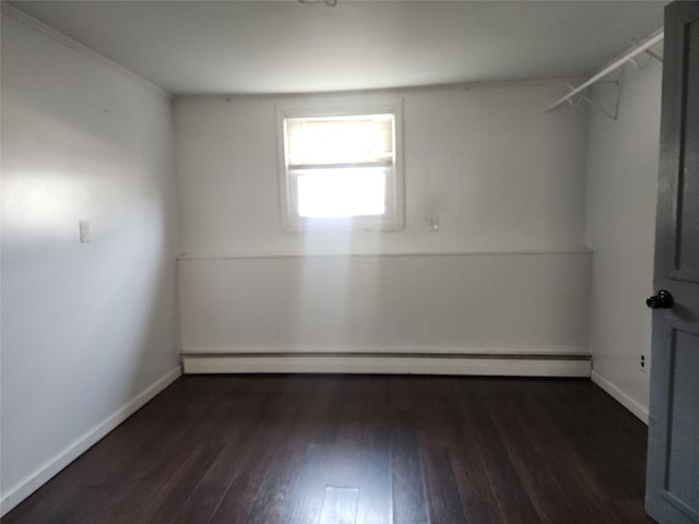 unfurnished room with a baseboard heating unit, baseboards, and dark wood-style flooring