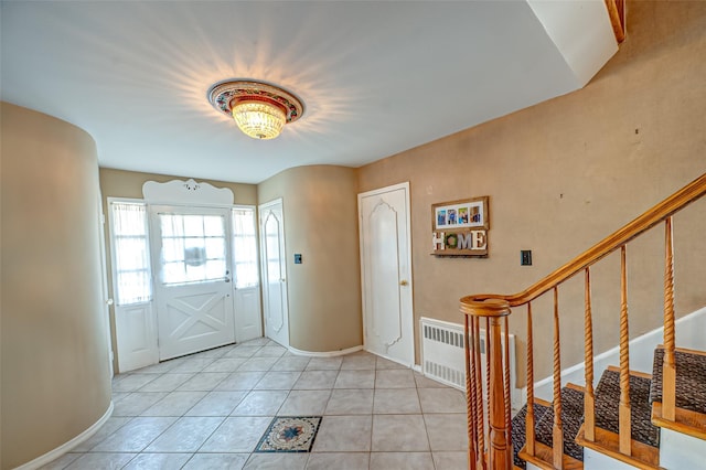 foyer with baseboards, radiator, light tile patterned flooring, and stairs