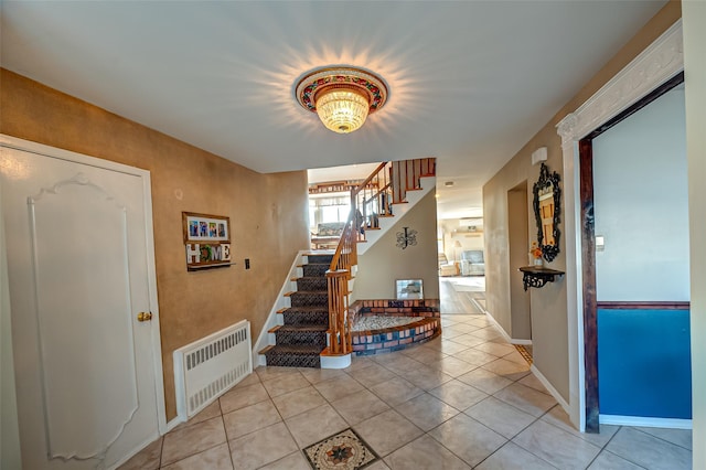 entryway featuring light tile patterned floors, stairway, radiator heating unit, and baseboards