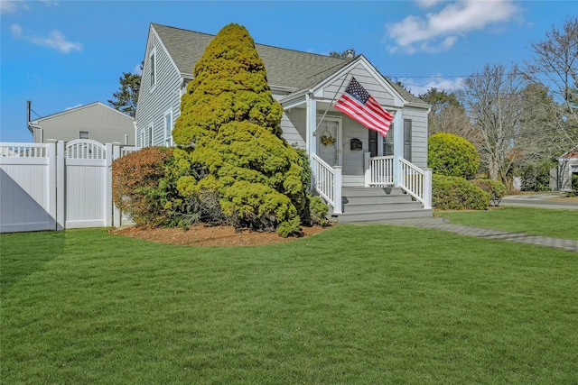 view of front of property featuring a shingled roof, fence, a front lawn, and a gate