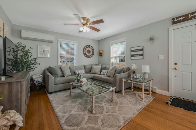 living area featuring a wall mounted air conditioner, a baseboard heating unit, wood-type flooring, baseboards, and ceiling fan