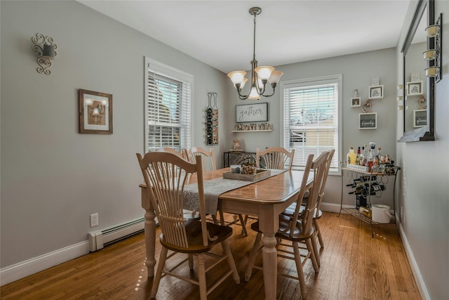 dining room featuring baseboards, baseboard heating, an inviting chandelier, and hardwood / wood-style floors