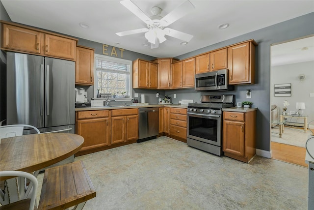 kitchen with baseboards, light countertops, appliances with stainless steel finishes, brown cabinetry, and a ceiling fan