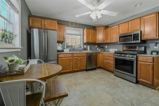 kitchen featuring light countertops, brown cabinets, appliances with stainless steel finishes, a ceiling fan, and a sink