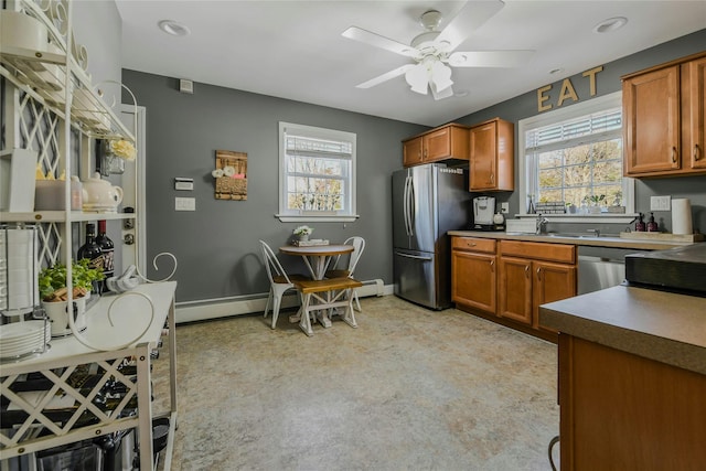 kitchen featuring a ceiling fan, brown cabinetry, baseboards, and appliances with stainless steel finishes