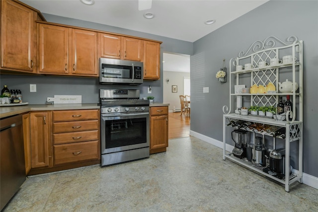 kitchen with brown cabinetry, stainless steel appliances, and baseboards