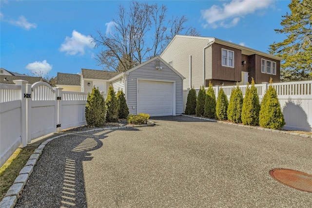 view of property exterior featuring a gate, an outdoor structure, a garage, and fence