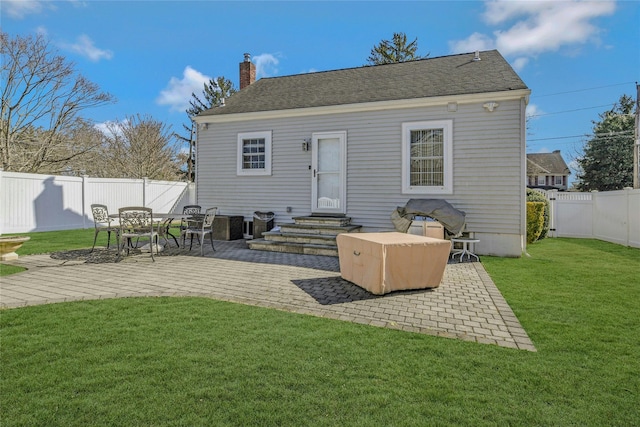 back of property featuring entry steps, a lawn, a chimney, a fenced backyard, and a patio area