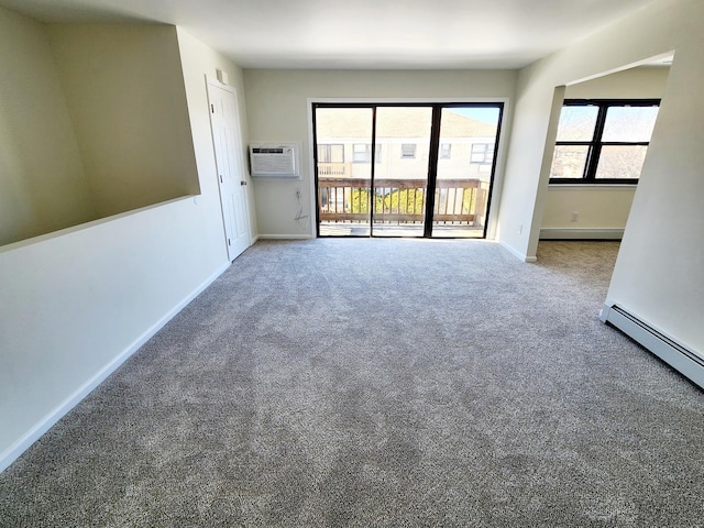 empty room featuring a wealth of natural light, baseboard heating, carpet flooring, and a wall unit AC