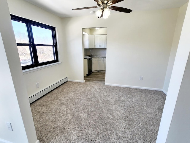 unfurnished bedroom featuring a sink, a baseboard heating unit, baseboards, and carpet