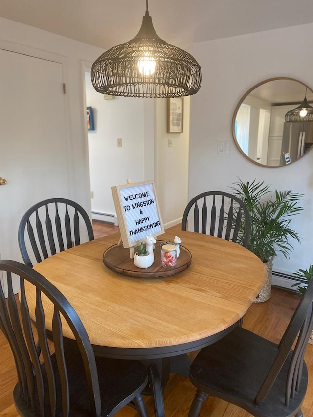 dining area featuring a baseboard radiator and wood finished floors