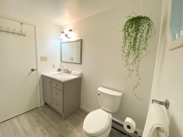 bathroom with toilet, a baseboard radiator, vanity, and wood finished floors