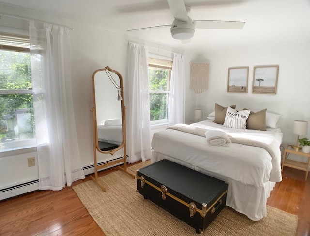 bedroom with light wood-type flooring, a baseboard heating unit, and ceiling fan