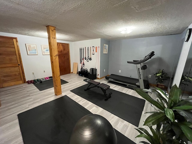 workout area with light wood-style floors and a textured ceiling