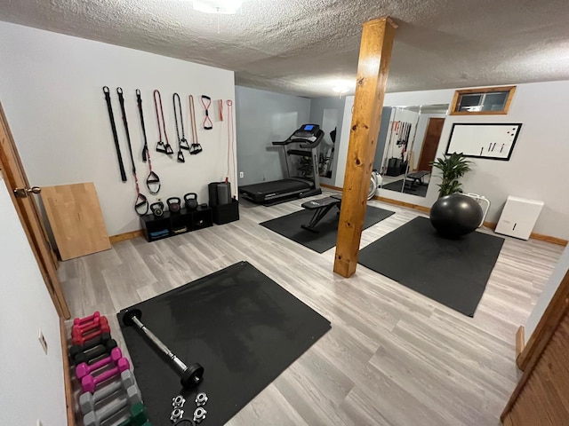 exercise room featuring baseboards, wood finished floors, and a textured ceiling