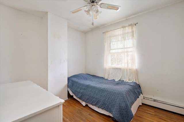 bedroom featuring a ceiling fan, light wood-style floors, and baseboard heating