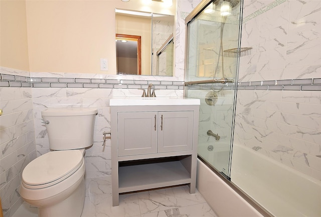 full bath with toilet, vanity, combined bath / shower with glass door, marble finish floor, and tile walls