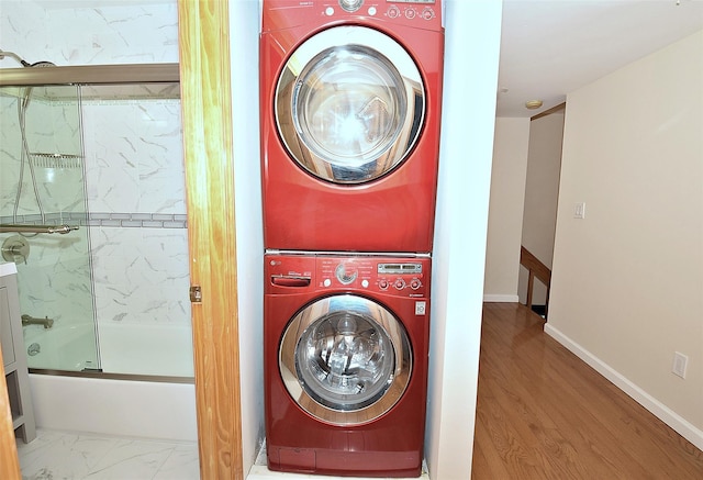 laundry area featuring marble finish floor, stacked washer / drying machine, and baseboards