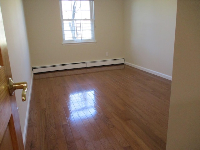 spare room with a baseboard radiator, baseboards, and wood finished floors