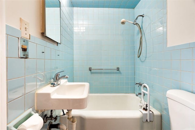 full bathroom featuring a sink, shower / bathing tub combination, toilet, and tile walls